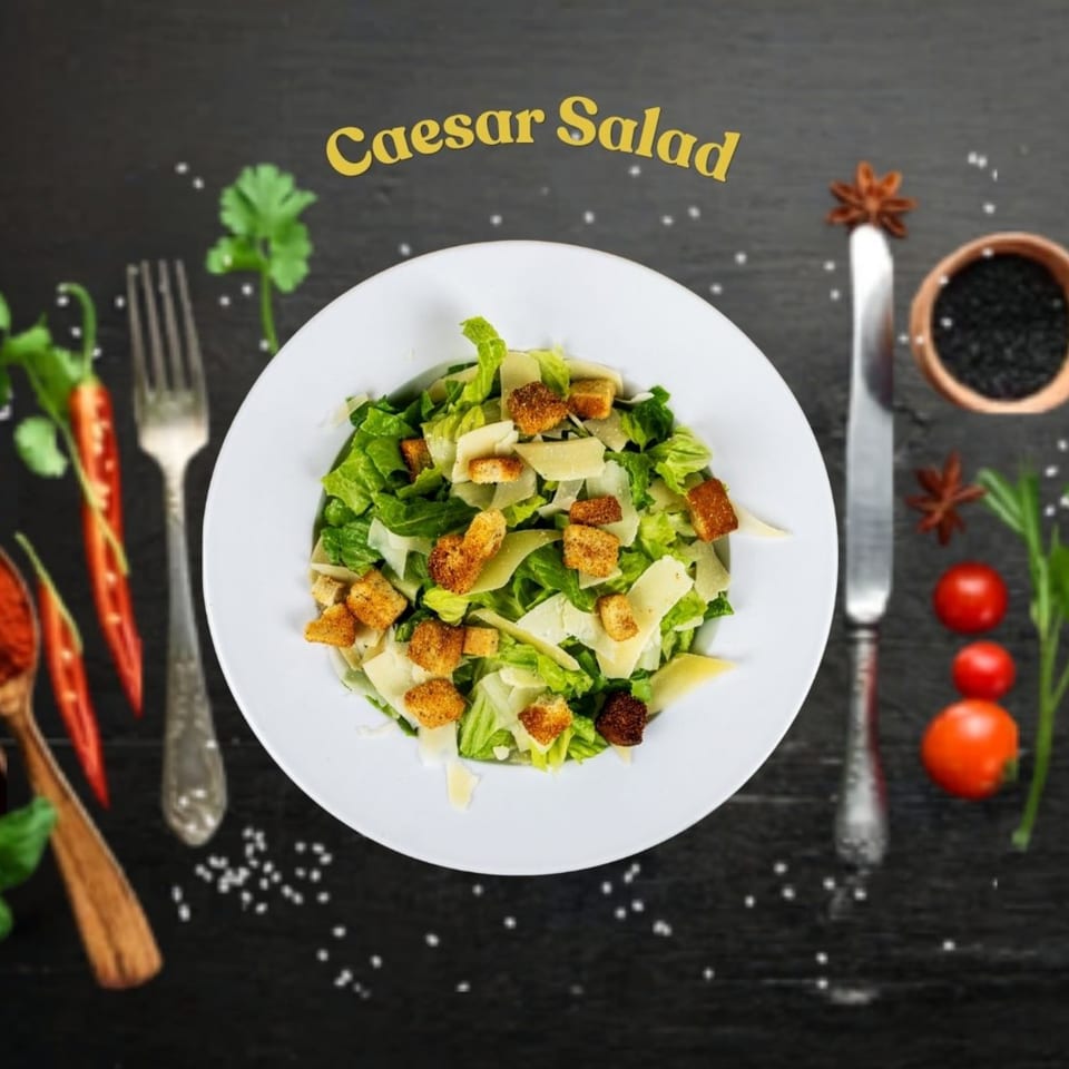 Caesar salad with croutons and parmesan cheese, garnished with spices and vegetables on a dark surface.