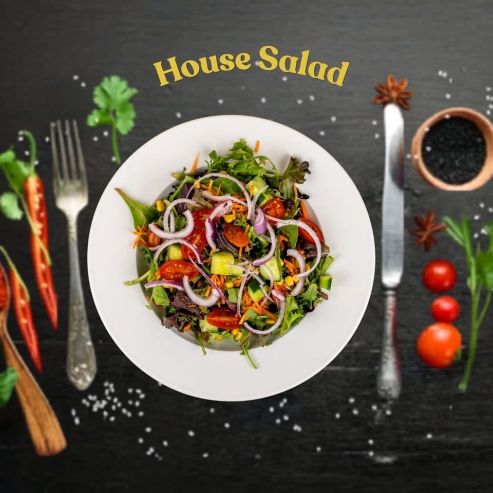 A vibrant house salad with mixed greens, tomatoes, cucumbers, onions, and corn on a dark surface.